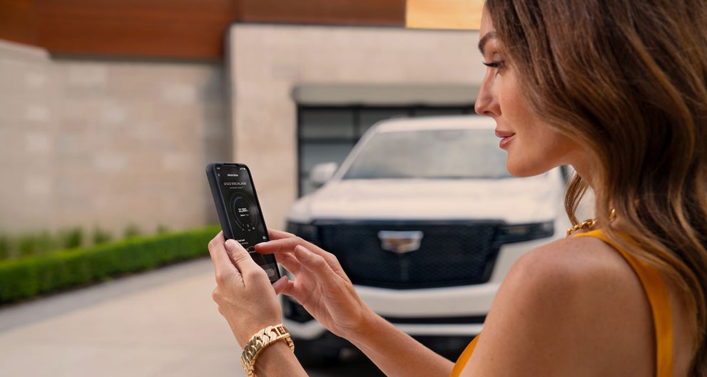 lady checking her mobile with a Cadillac vehicle background | Reliable Cadillac in Roseville CA